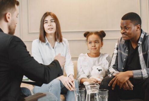 family-counseling-session-home-with-therapist-pshycologist-showing-pictures-emotions-girl-african-american-father-european-mother_1157-47489 (1)